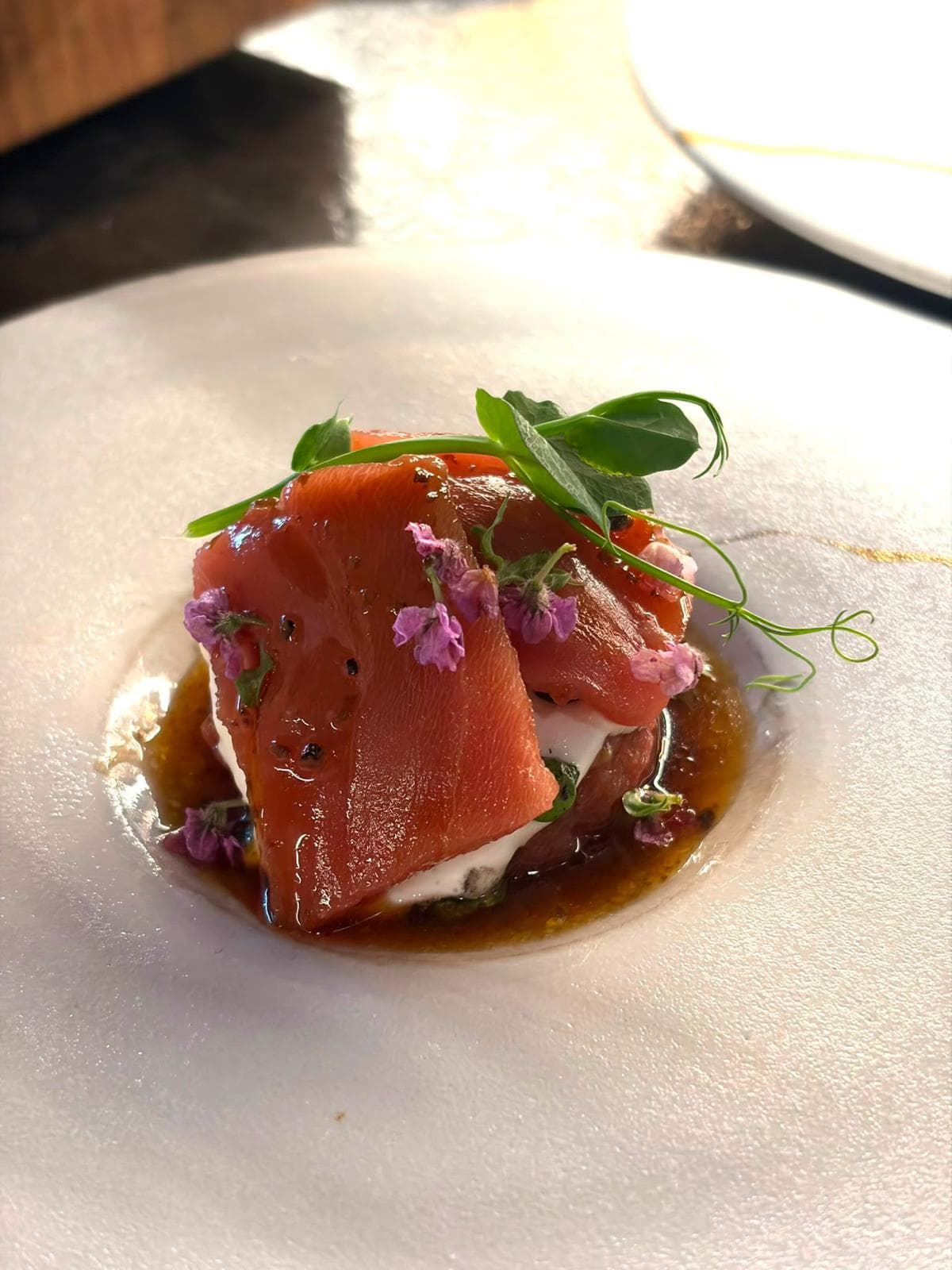 A plated tuna dish garnished with pea shoots and edible flowers