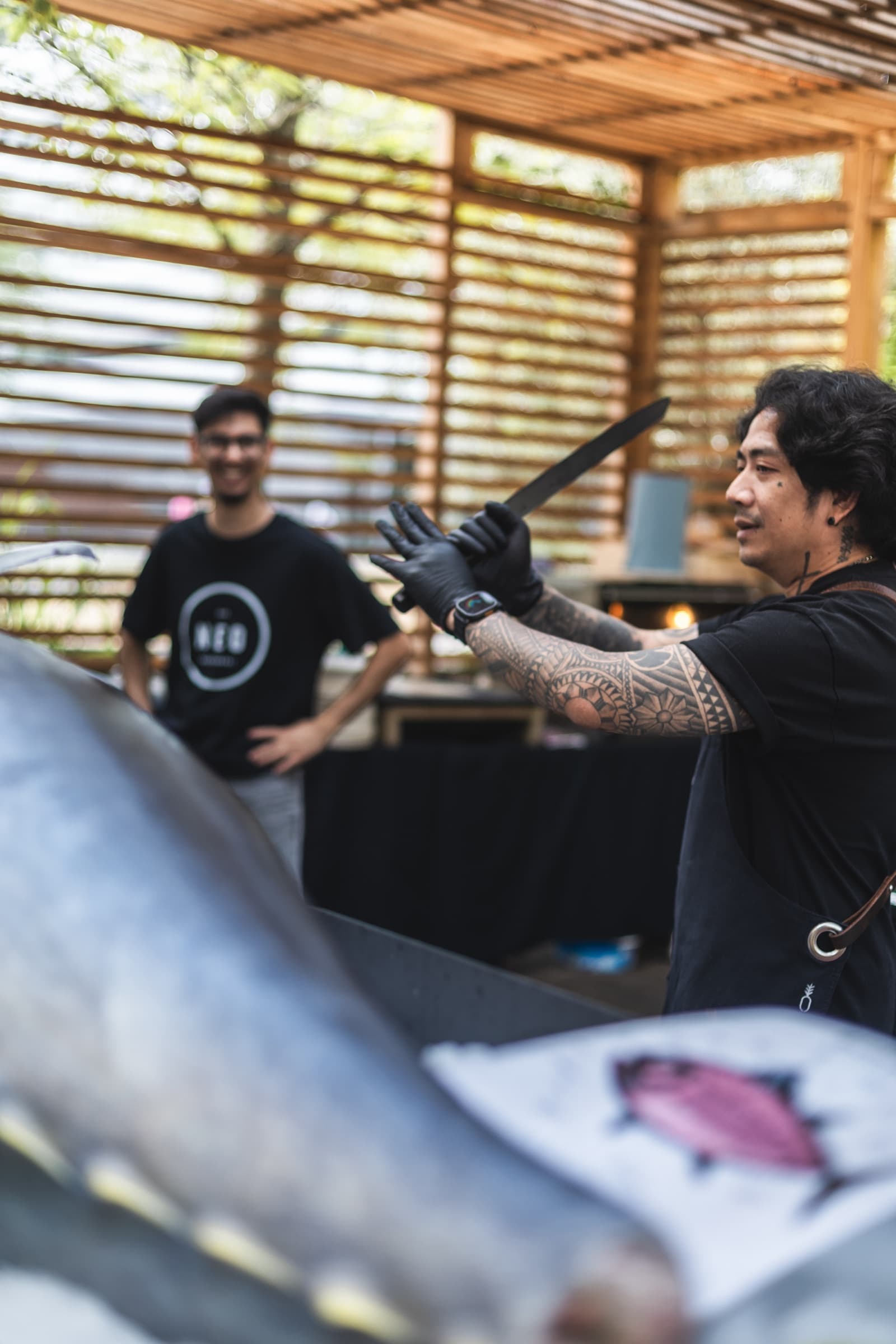 A chef presenting a live tuna cutting show, knife raised over a whole bluefin tuna