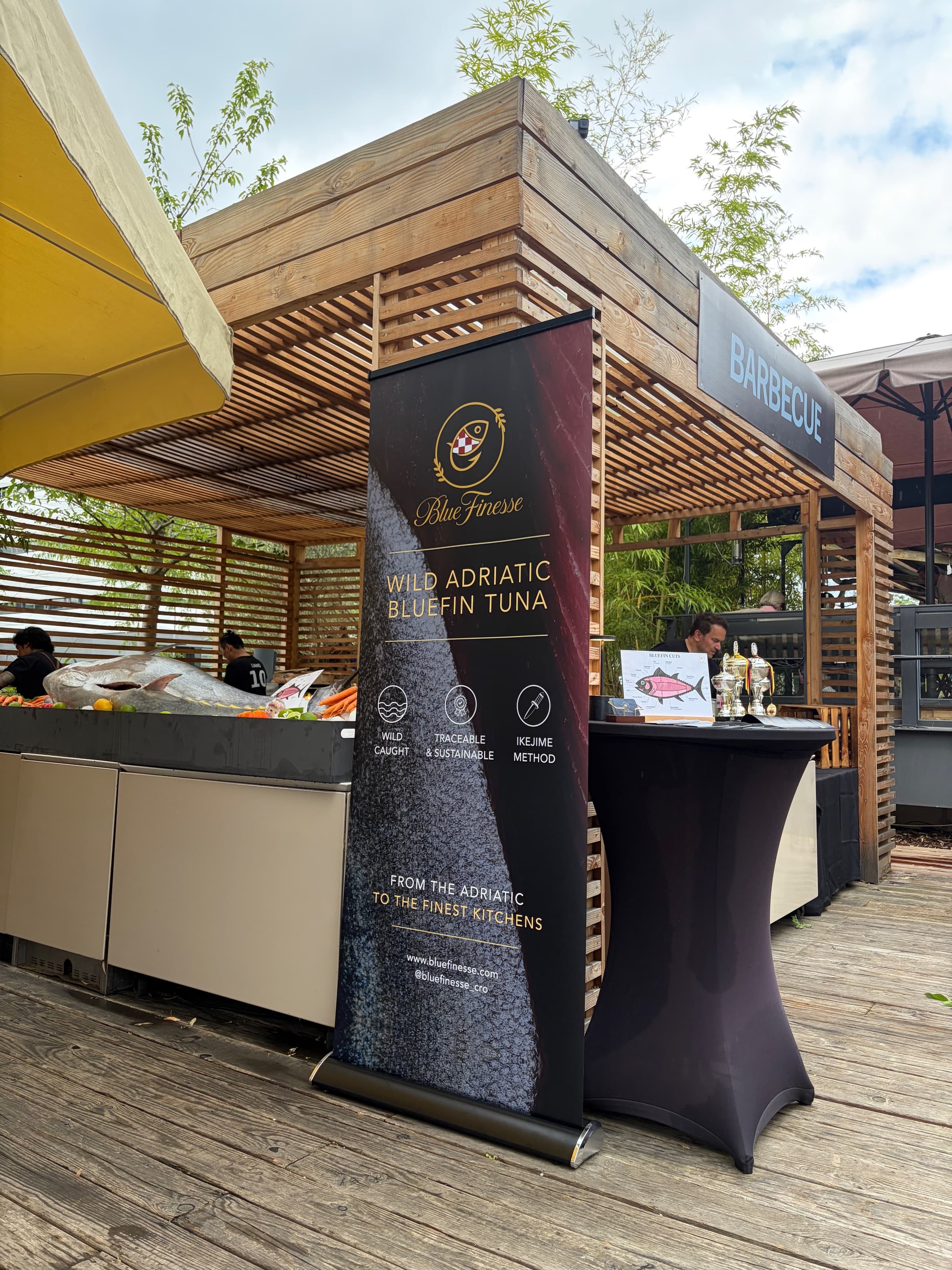 A BLUE FINESSE banner beside a whole tuna on ice at a live tuna cutting event